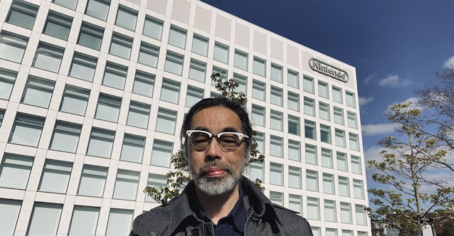 Imagem de Takaya Imamura, um senhor de idade japonês, em frente ao prédio da Nintendo no Japão.